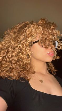 a close up of a person with curly hair and glasses in front of her face