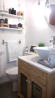 a bathroom with a sink, toilet and shelves on the wall above it's mirror