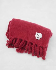 a close up of a red blanket on a white surface with a tag attached to it