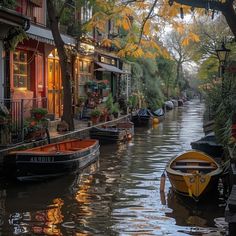 several boats are parked on the side of a canal in front of buildings and trees