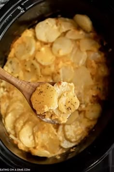 a wooden spoon in a crock pot filled with potato casserole and potatoes