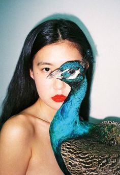 a woman is holding a peacock with her face painted like a lady's head