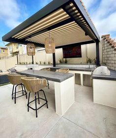 an outdoor kitchen with bar stools and grill