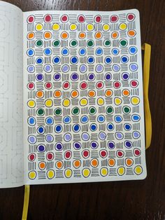 an open notebook with colored circles on the cover and yellow ribbon around it, sitting on a wooden table