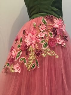 a pink tulle skirt with flowers and leaves on the bottom, in front of a mannequin's torso