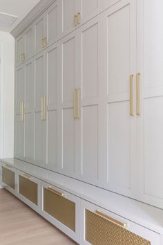 a large white cabinet with gold handles in a room that has hardwood floors and walls