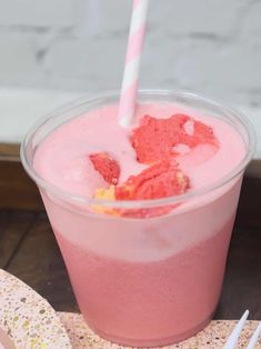 a pink drink in a plastic cup with a straw