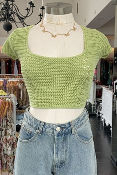 a female mannequin with a green crop top on it's head and some clothes in the background