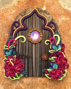 an image of a fairy door with flowers on the front and side doors painted in different colors