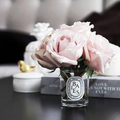 a glass vase filled with pink roses sitting on top of a table next to two books