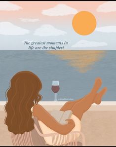 a woman sitting on top of a beach next to a glass of wine