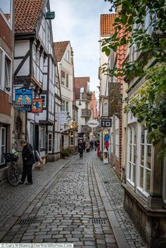 an old cobblestone street with people walking down one side and shops on the other