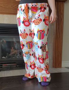 a person standing in front of a fire place with an owl print pajama pants on