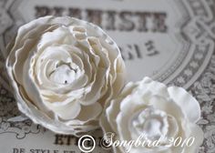 two white flowers sitting on top of an old fashioned paper card with the words paris written in french