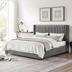 a bedroom with white walls and wood floors, two framed pictures on the wall above the bed