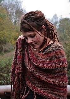 a woman with dreadlocks wrapped around her neck wearing a red and brown shawl