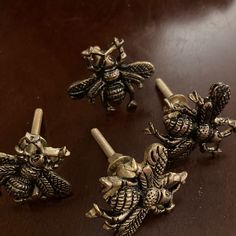 three antique brass bee knobs sitting on a table