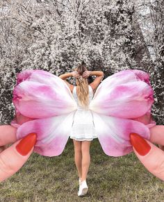 a woman holding a pink and white butterfly in her hands