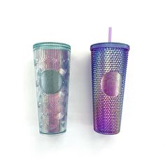 two different colored tumblers sitting next to each other on a white surface, one with a purple straw