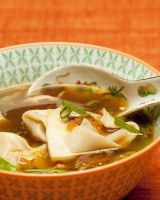 a bowl filled with dumplings and soup on top of an orange cloth covered table