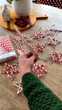 a person is decorating some red and white candy canes on a wooden table