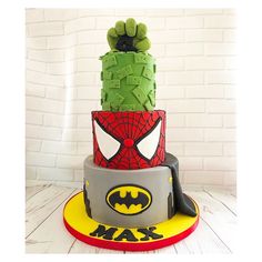 a three tiered cake decorated with fondant and icing, featuring the face of spider - man