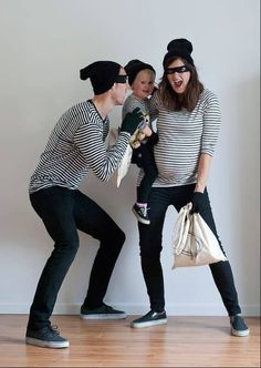 two women and a baby are standing in front of a wall with their mouths open