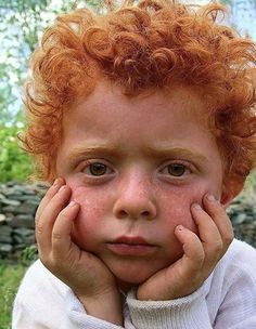 a young boy with red hair and freckles on his face is looking at the camera