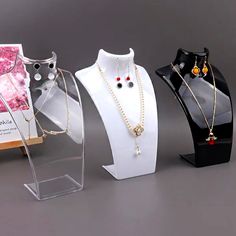 three necklaces are on display in front of a card holder with a book and other jewelry