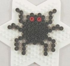 a white star shaped object with black beads and red eyes on the center, in front of a gray background