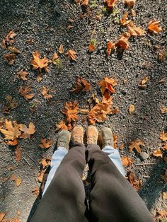 the person is standing in front of some leaves on the ground with their feet up