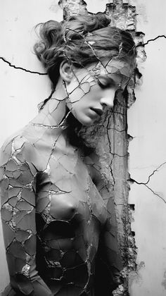 black and white photograph of a woman with cracked paint on her body, looking down at the ground