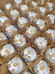 there are many cupcakes that are in the box on the table and one is decorated with white flowers