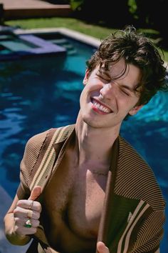 a man with no shirt standing in front of a swimming pool giving the thumbs up sign