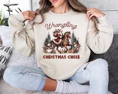 Western Christmas Cowboy Santa Sweatshirt, Wrangling Christmas Cheer Shirt, Santa Shirt, Cowboy Santa Sweater, Western Christmas Gift Sizing and Colors: Please refer to the size chart on the listing photos in every listing for a detailed sizing chart with measurements. Since all shirts are made to order, sizing issues will not be refunded. All T-SHIRTS brands are either Bella Canvas or Gildan. How Do I Order 1 - Please review all the information provided before placing an order 2 - Select the sh Christmas Cowboy, Cowboy Santa, Cheer Shirt, Santa Sweater, Cowboy Shirt, Santa Shirt, Cheer Shirts, Santa Shirts