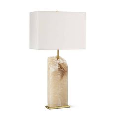 a table lamp with a white shade on the base and a gold plated metal base