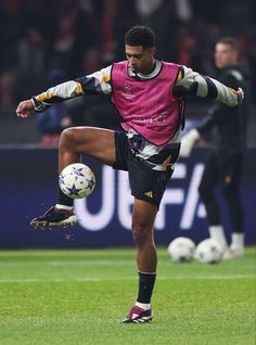 a man kicking a soccer ball on top of a field