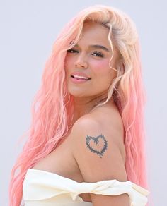 a woman with pink hair and tattoos on her shoulder