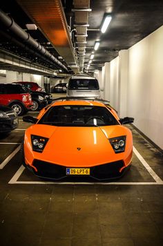 an orange sports car parked in a parking garage