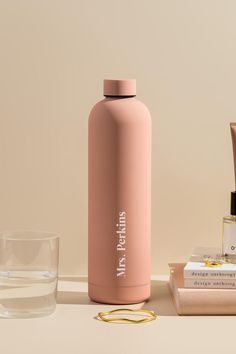 a pink water bottle sitting on top of a table next to a glass and toothbrush