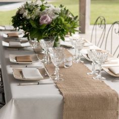 a long table set with place settings and flowers in vases on the top row