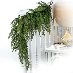 a christmas garland hanging from the side of a banister next to a lamp on a table