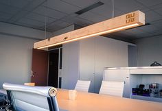 an empty conference room with white chairs and a light fixture hanging from the ceiling above it