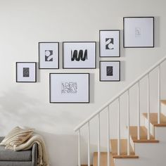 a living room filled with furniture and pictures on the wall next to a stair case