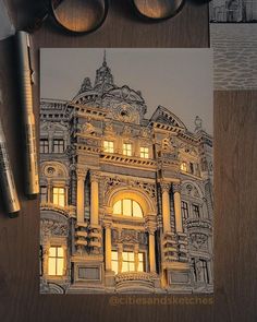 an old building lit up at night with some glasses on the table next to it