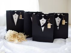 four black paper bags with white tuxedos on them