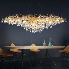 a chandelier hanging over a dining room table with chairs and vases on it