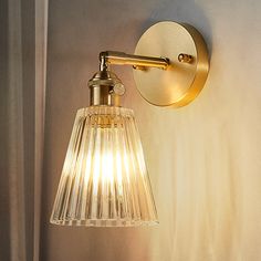 a light that is on the side of a wall next to a lamp fixture with a glass shade