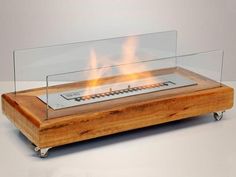 a wooden table with a glass top on wheels and flames in the middle that reads, j c moviss risicos