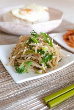 a white plate topped with noodles and veggies on top of a wooden table